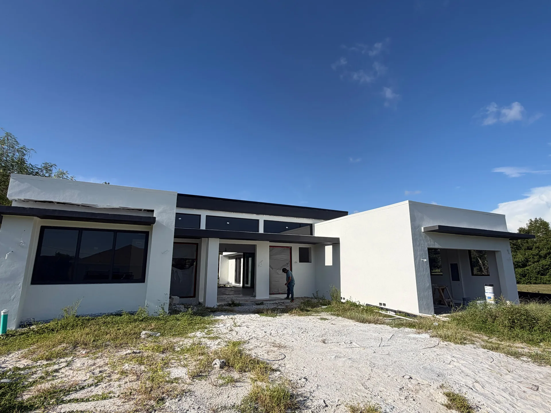 Wide Cape Coral exterior during painting, with light volumes and black-framed windows; work remains unfinished.