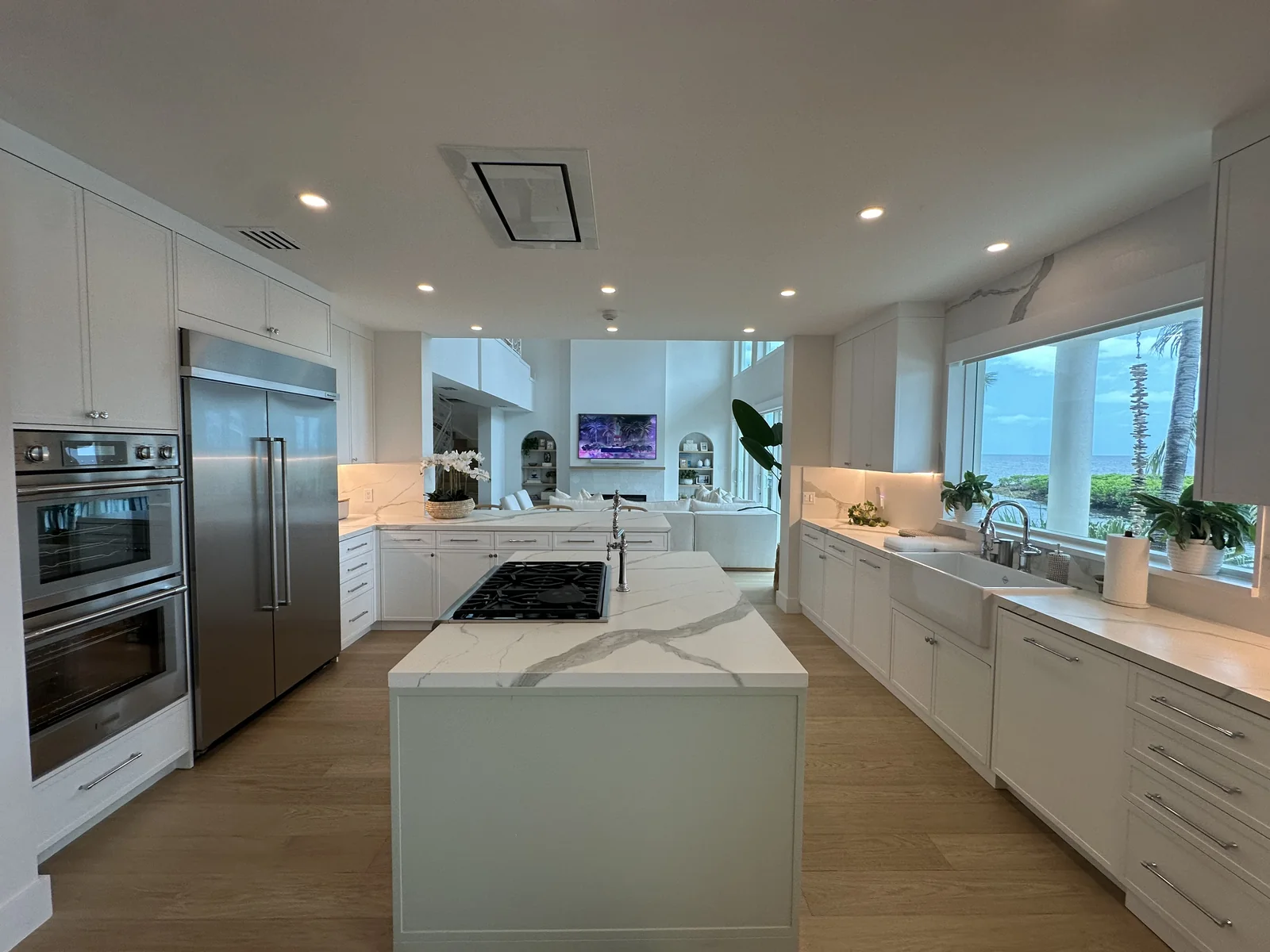 Coral Gables kitchen with an island, white cabinetry and large windows.